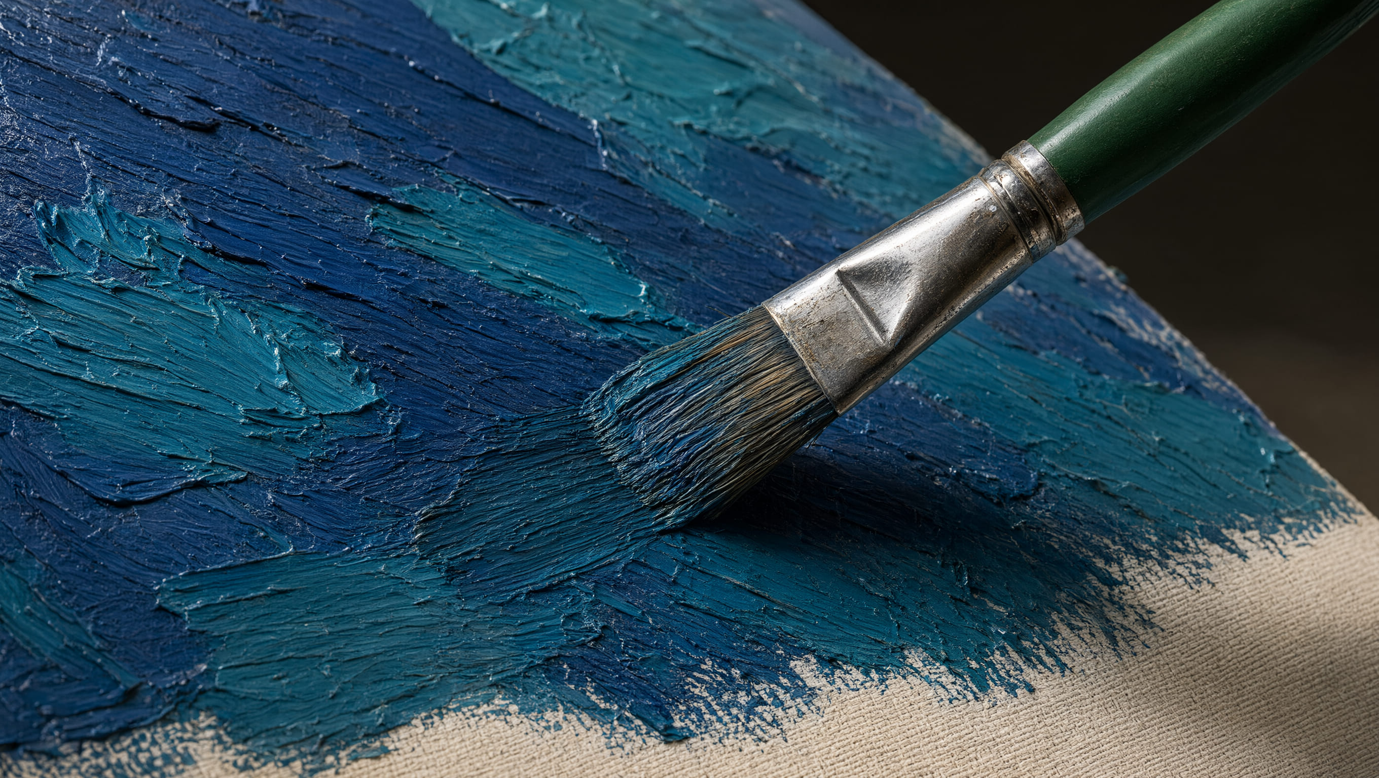 Paintbrush applying thick blue acrylic paint across a textured canvas surface.